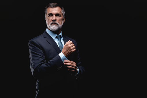 Handsome confident mature business man isolated on black background