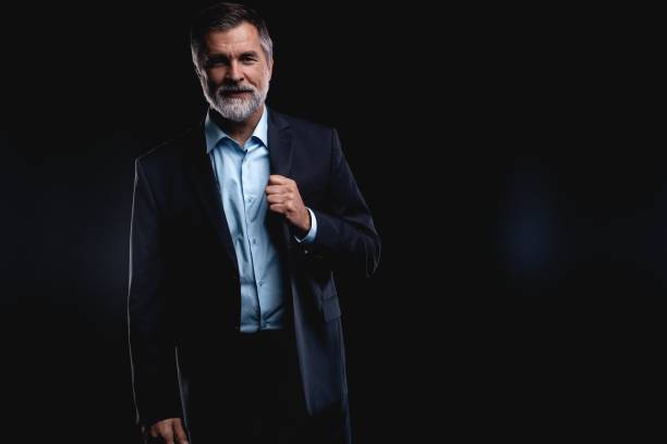 istock Handsome mature business man isolated on black background 1075457244