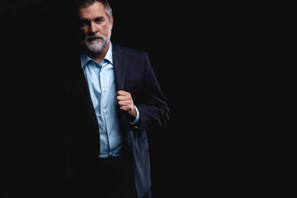 istock Handsome mature business man isolated on black background 1075457320