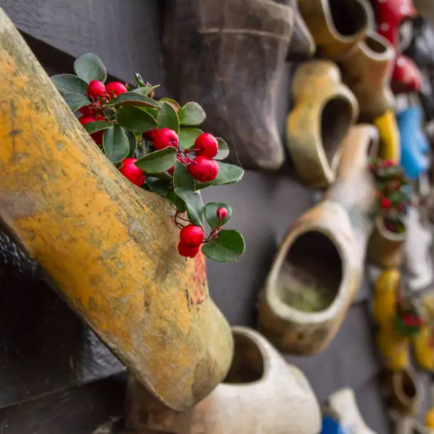 Composition on the wall from traditional dutch wooden shoes - klompen (clogs), decorated with flowers, closeup, the Netherlands