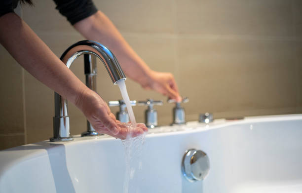 turning on the water of bathtub stock photo