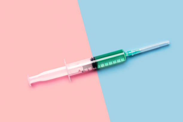 Syringe with green liquid on pink and blue
