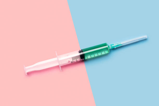 Syringe with green liquid on pink and blue Large 10 ml plastic syringe with bright green liquid on bright pink and blue background shot with studio light from above milliliter stock pictures, royalty-free photos & images