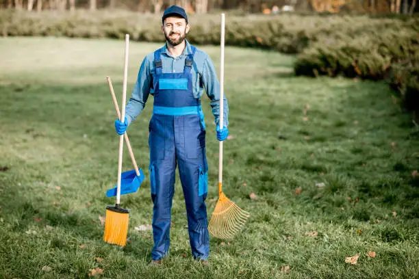 Photo of Professional sweeper with cleaning tools outdoors