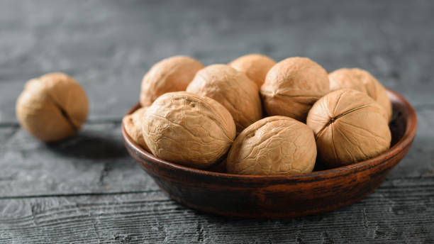 istock Walnuts in a clay bowl on a dark wooden table. 1075506976