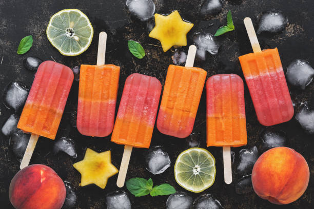 istock Peach popsicles with fruit, lemon and ice cubes on a dark background. Top view, flat lay. 1075517958