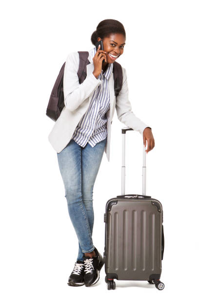 istock happy young black woman with suitcase standing against isolated white background while talking on cellphone 1075520998