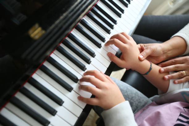 音楽教師は彼女の学生に教えるピアノを弾きます。 - music child pianist learning ストックフォトと画像