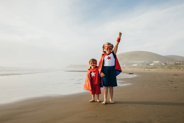 jeune fille et garçon super héros sur la plage de californie - partnership creativity superhero child photos et images de collection