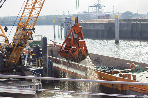 Digger is excavating sediments from the river bed inside the port Hamburg, Germany