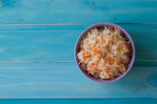 Photo of Photo of sauerkraut in a plate on a blue wooden background.