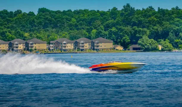 Colorful speedboat on water near cottages and treeline