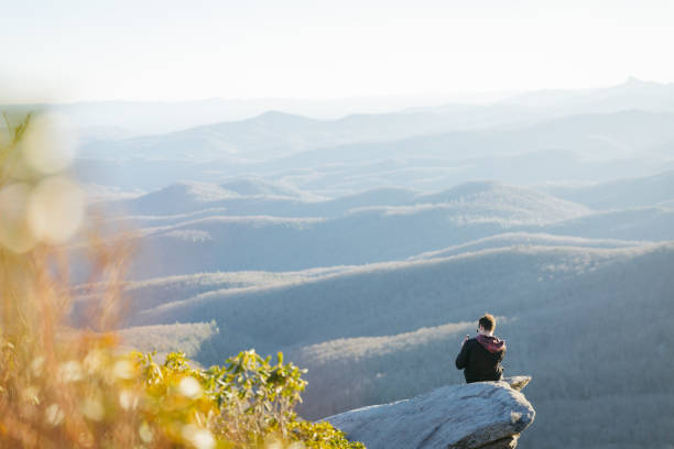 Man using phone sitting on a rock on the Blue Ridge Parkway in the fall