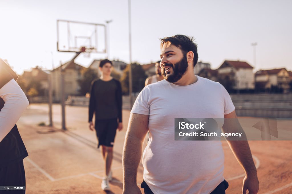 Game over Group of men friends going home after basketball match on street court Overweight Stock Photo