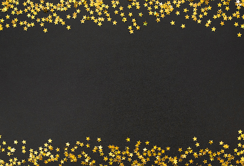 Festive background. Frame of Golden stars scattered on black background. Billboard or Web banner With Copy Space for text. Beautiful template for holiday greeting card