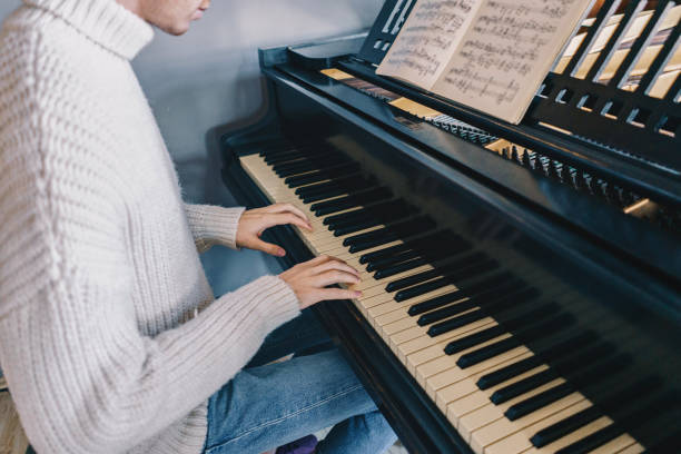 istock Man in sweater playing a piano at home 1075584216
