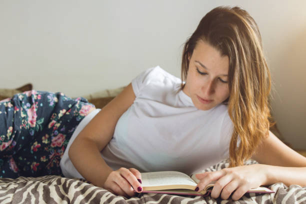 istock Cute caucasian girl lying in her bed and reading a book 1075585904