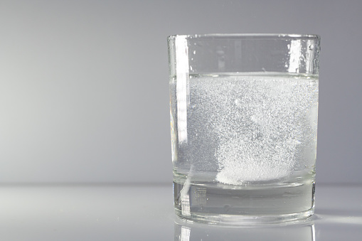 Glass with dissolvable effervescent tablet in water with bubbles
