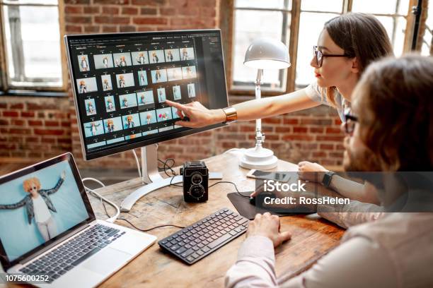 Couple Of Photographers Working On Computers In The Studio Stock Photo - Download Image Now