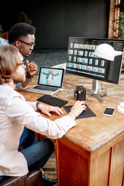 Two photographers working on the computers in the studio Two male photographers choosing woman's portraits at the working place with two computers in the studio photo editing screen stock pictures, royalty-free photos & images