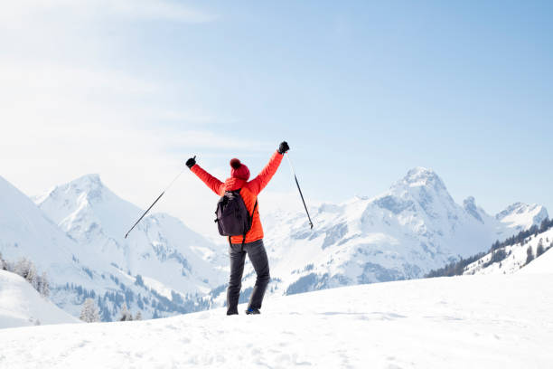 istock Female backpacker with arms raised in winter landscape 1075603400