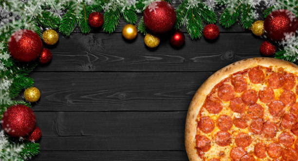 pizza salami weihnachten schneeflocke mit tannenzweigen und neujahr spielball, auf schwarzer holzplatte tisch - salami sausage portion decoration stock-fotos und bilder