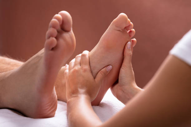 terapista che dà massaggio ai piedi all'uomo - massaging spa treatment health spa men foto e immagini stock