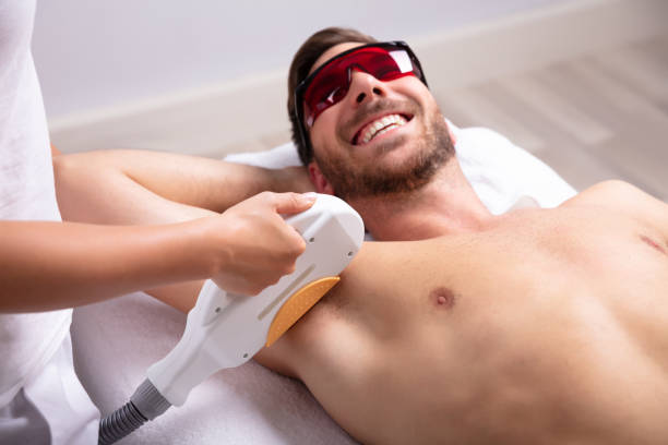 junger mann mit achsel laser-haarentfernung behandlung - haarentfernung durch elektrolyse stock-fotos und bilder