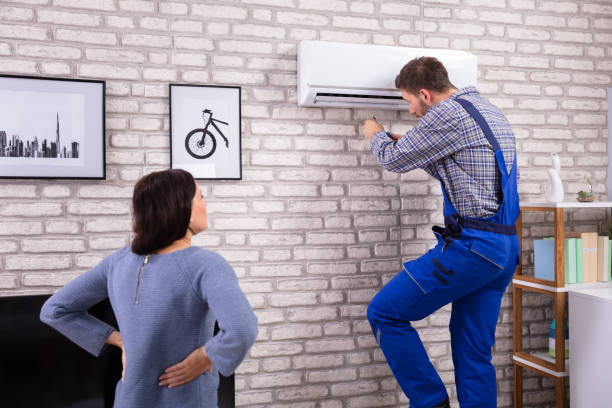 istock Woman Looking At Technician Repairing Air Conditioner 1075627992