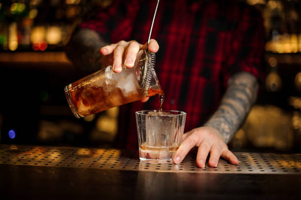 istock Barman pouring strong alcohol into a cocktail glass using strainer 1075634094