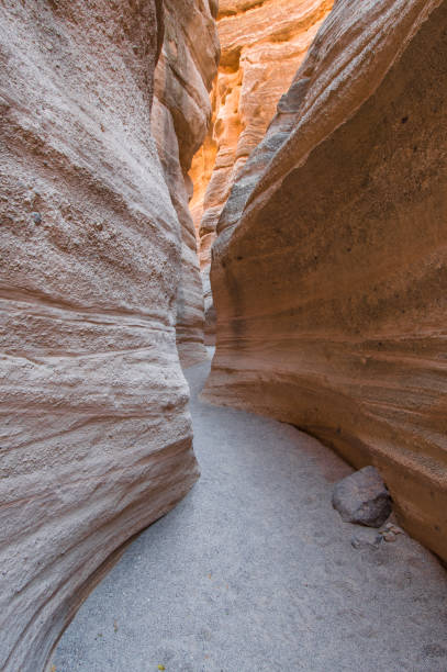 Path through a deep slot canyon with vertical walls showing wavy erosion patterns at Kasha-Katuwe Tent Rocks National Monument Slot canyon in Kasha-Katuwe National Monument, New Mexico USA kasha katuwe tent rocks stock pictures, royalty-free photos & images