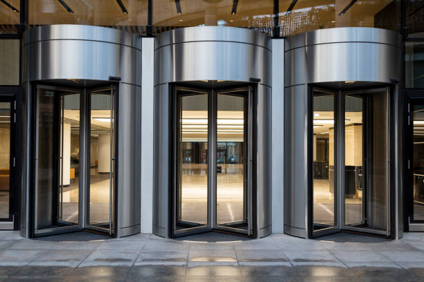 Entrance of Modern Office Building Glass-fronted office building entrance at dusk with revolving doors, London, United Kingdom bank entrance stock pictures, royalty-free photos & images