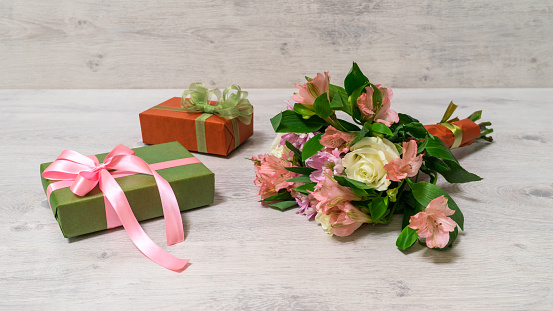 Colorful spring bouquet of rose, chrysanthemum and alstroemeria flowers with gift boxes on wooden background
