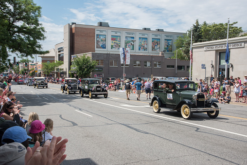 Naperville, Illinois, United States-May 29,2017: Procession of vintage cars with veterans and large crowds during the Memorial Day parade in downtown Naperville, Illinois