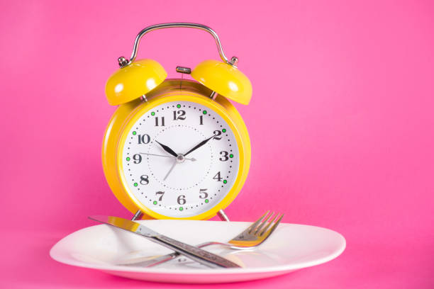 istock Clock with alarm and empty plate with knife and fork. Chrono diet concept 1075698164