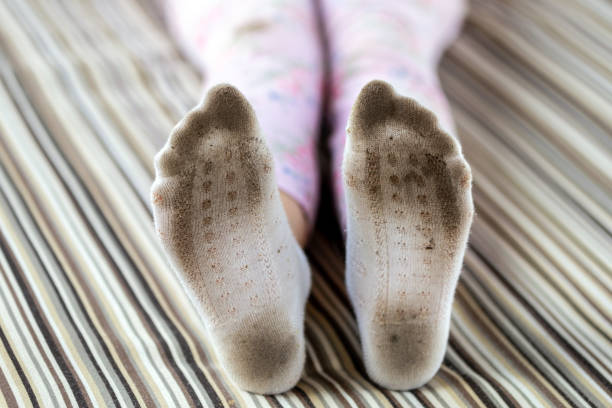 Pair of child feet in dirty stained white socks. Kid soiled socks while playing outdoors. Children clothes bleaching and washing troubles concept Pair of child feet in dirty stained white socks. Kid soiled socks while playing outdoors. Children clothes bleaching and washing troubles concept. kids dirty shoes stock pictures, royalty-free photos & images