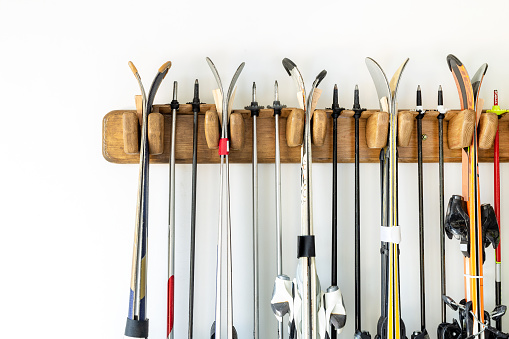 Lot of ski hanged on customized wooden wall mount at garage for seasonal storage. Extreme winter sport equipment handling at home warehouse.