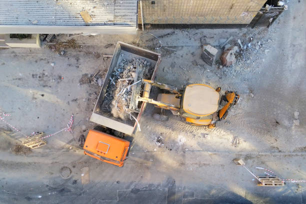 istock Bulldozer loader uploading waste and debris into dump truck at construction site. building dismantling and construction waste disposal service. Aerial drone industrial background 1075711174