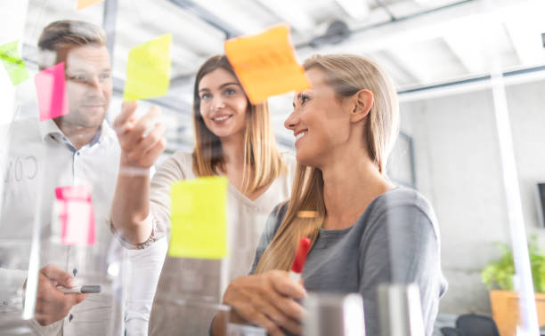 Young creative business people meeting at office. Business people meeting at office and use post it notes to share idea. Brainstorming concept. Sticky note on glass wall. office fun business adhesive note stock pictures, royalty-free photos & images