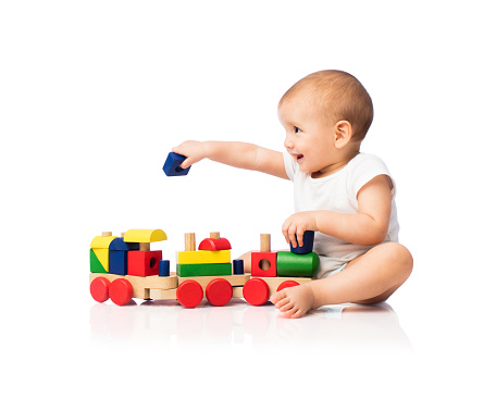 A cheerful latin baby boy playing with toy blocks, looking away and smiling.
