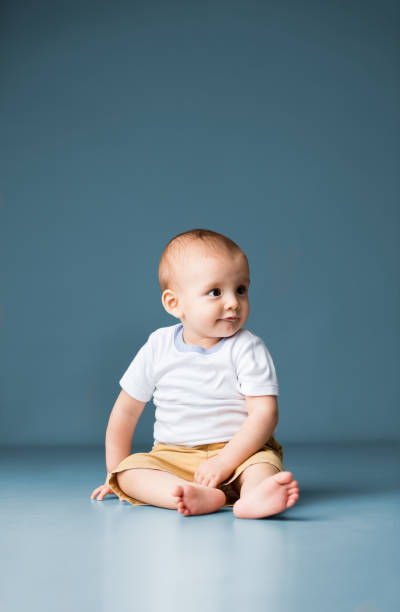 istock Cute baby boy sitting on floor and looking away 1075739520