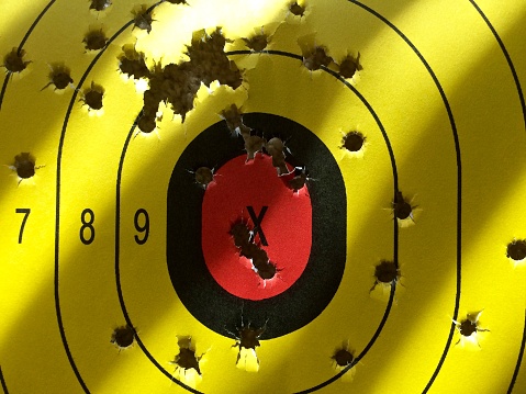 yellow target with holes from bullets