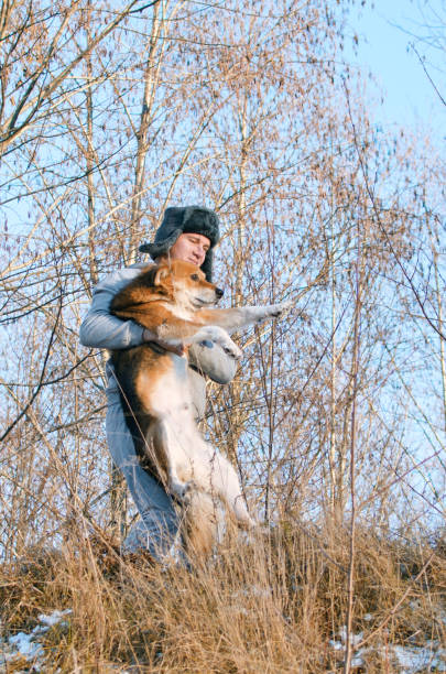 young man carries a dog through the impassable winter forest