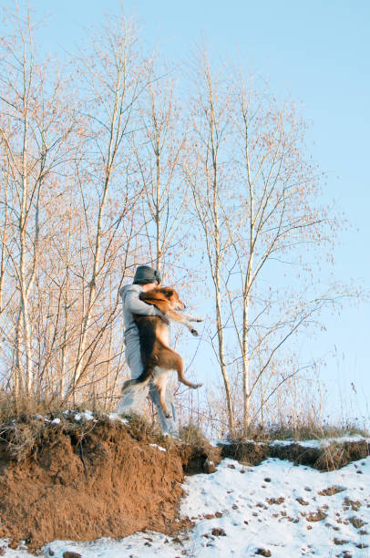 young man carries a dog through the impassable winter forest