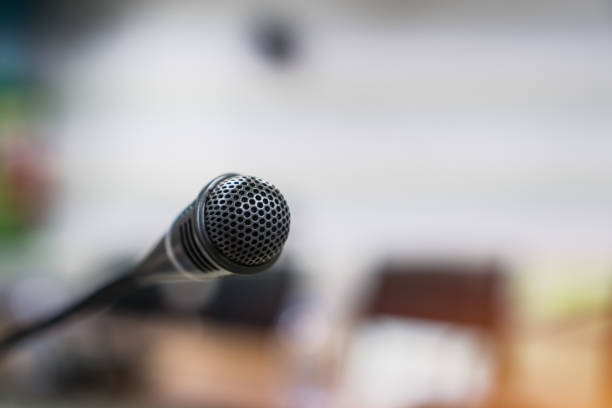 istock Mini Microphone on abstract blurred conference hall for speaker on stage in seminar room background, Business meeting and education in teaching classroom concept 1075792710