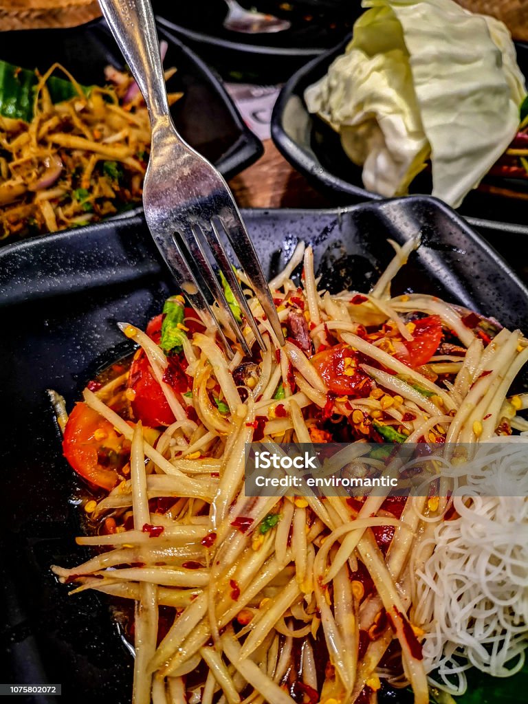 Som Tam, a popular and favorite Thai food dish made of young sliced papaya, chili, tomatoes and palm sugar. Som Tam, a popular and favorite Thai food dish made of young sliced papaya, chili, tomatoes and palm sugar. This dish is popular in the North and North Eastern part of Thailand. Asia Stock Photo