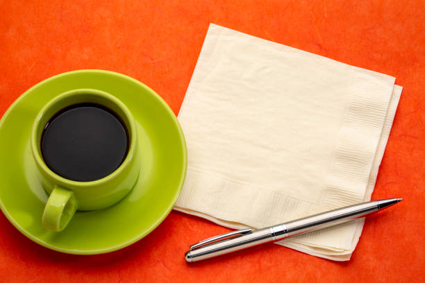 color abstract - green cup of espresso coffee with a napkin and pen against red mulberry paper