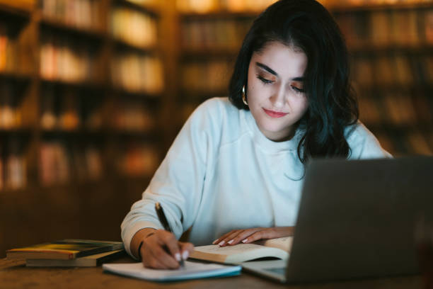 young college student studying at library - online university imagens e fotografias de stock