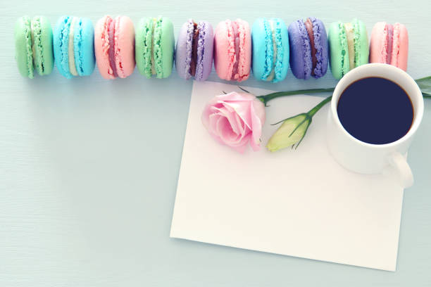 istock plate of macaroons over wooden table cofee, empty note and flowers. 1075862062