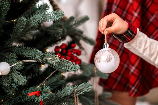 小さな子供の手を飾るクリスマス ツリー室内。 - christmas ball christmas ornament human hand ストックフォトと画像